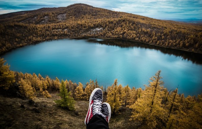 osoba siedząca na górce z widokiem na jezioro